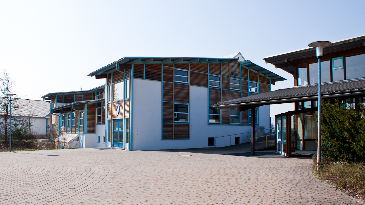 Aussenperspektive Sportlerheim mit nebestehender Brühlhalle, Fassadegestaltung Putz und Pfosten-Riegel-Konstruktion Türkis ausgefacht mit Lärche Stülpschalung