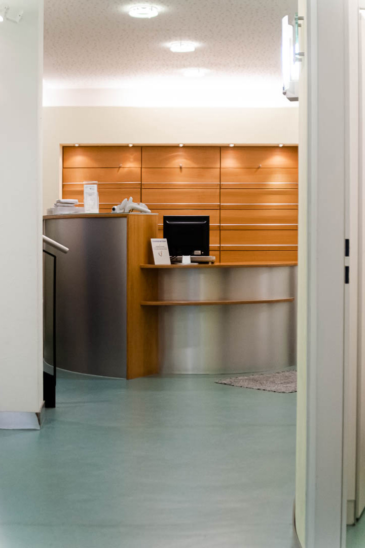 Individuell gestalteter Empfangstresen mit Arbeitsbereich und Aktenschrank in Holz- und Metalloptik