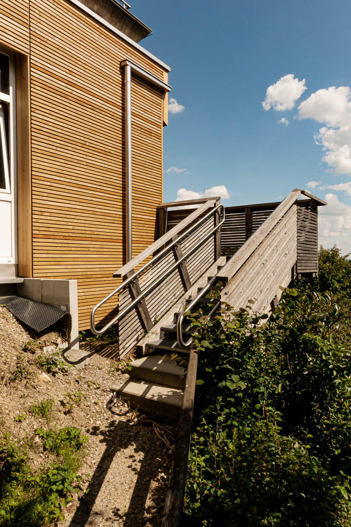 Blick von unten auf neue Fluchttreppe. Geländer mit Holzschalung Lärche Paralellogrammfassade